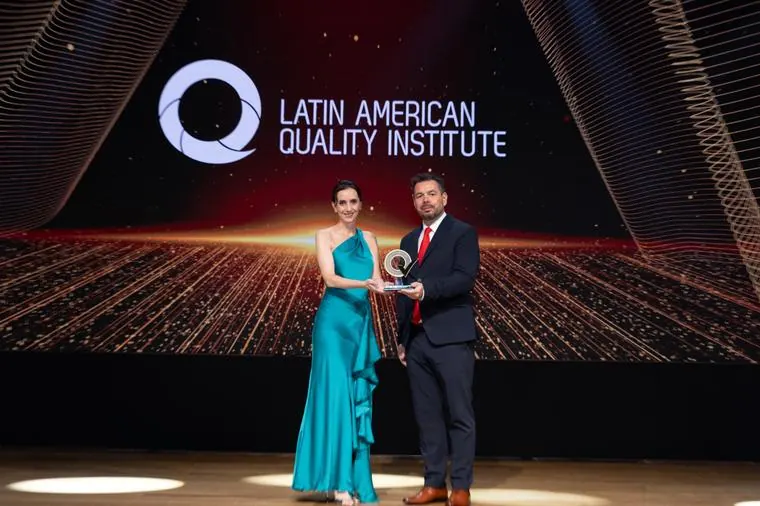Entrega de reconhecimento no palco com a projeção LAQI