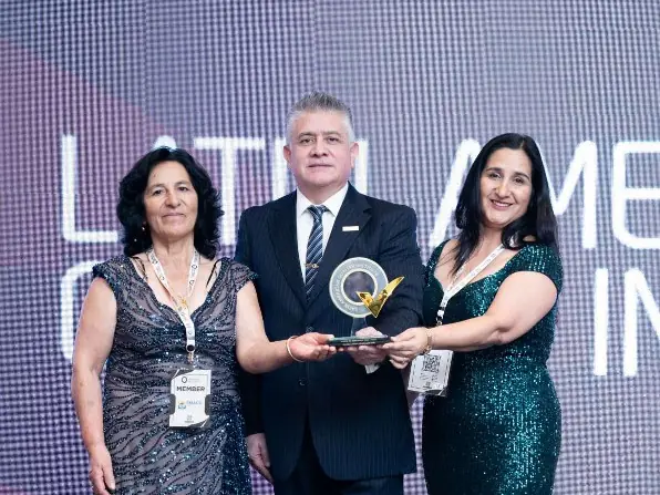 Entrega de trofeo en el escenario de la premiación con la imagen LAQI