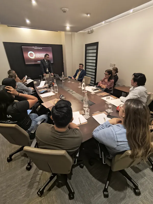 Reunión de trabajo con periodistas y miembros en una sala con la marca LAQI en la pantalla